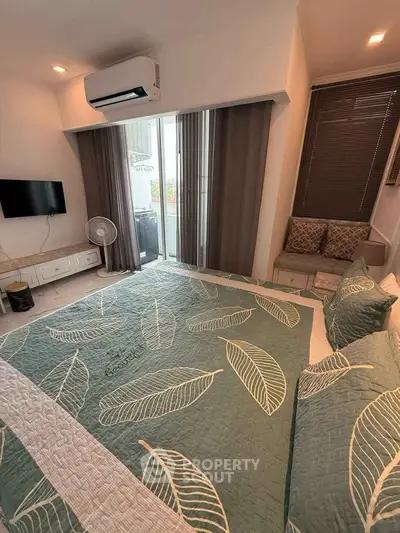 Cozy bedroom with modern decor and balcony access, featuring air conditioning and stylish bedding.