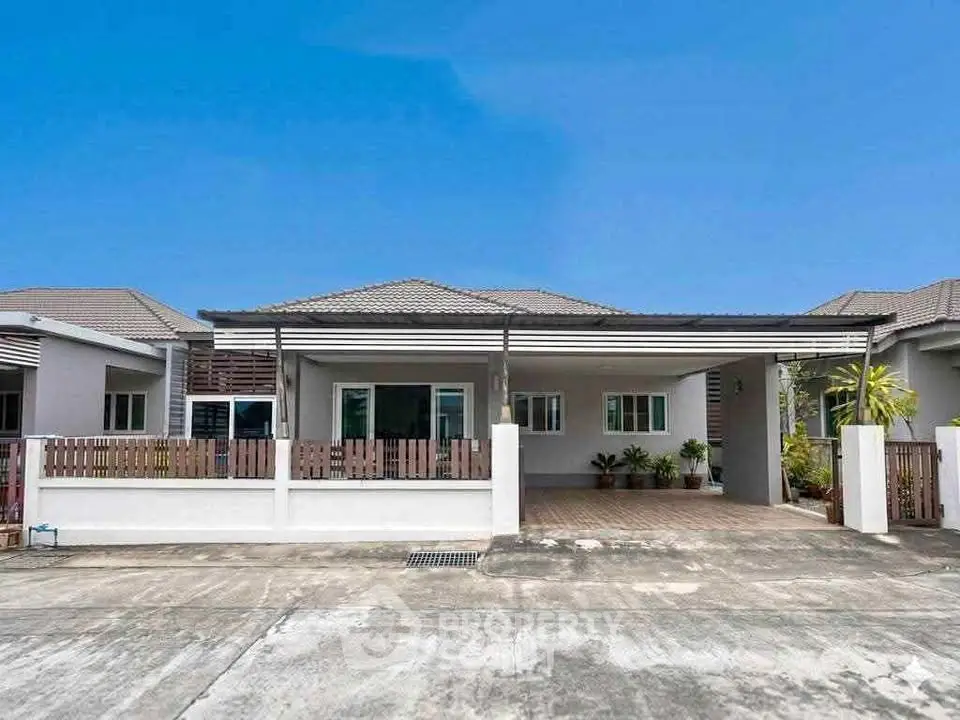 Charming single-story home with spacious driveway and modern facade under clear blue skies.