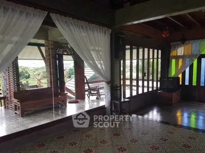 Charming open-layout living room with vintage tiles and panoramic windows overlooking lush greenery.