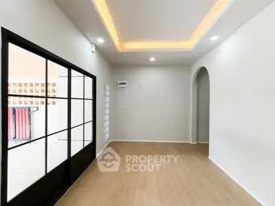 Spacious modern living room with elegant ceiling lights and large glass doors opening to a balcony.