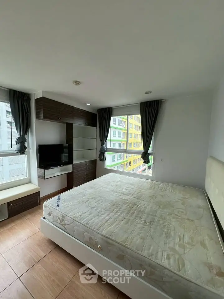 Spacious bedroom with large windows and modern furnishings in a high-rise apartment.