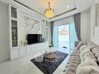 Luxurious living room with elegant decor and pool view, featuring plush sofa and modern entertainment center.