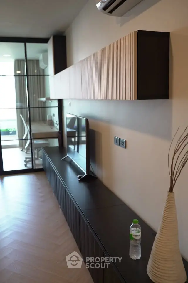 Modern living room with sleek TV stand and glass door leading to balcony
