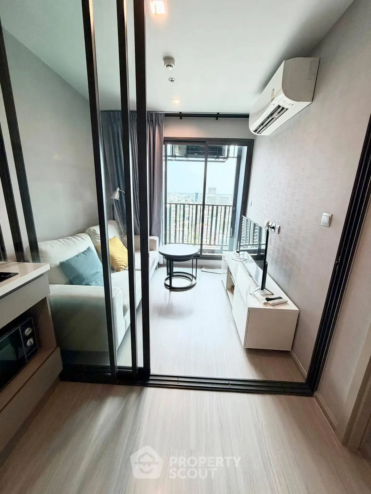Modern living room with balcony view in a stylish apartment, featuring sleek furniture and air conditioning.