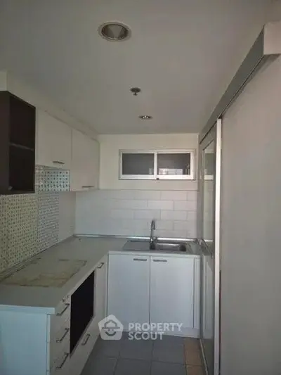 Compact modern kitchen with sleek white cabinetry and built-in appliances.