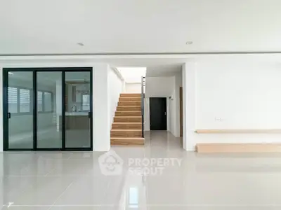 Spacious modern living room with sleek staircase and sliding glass doors