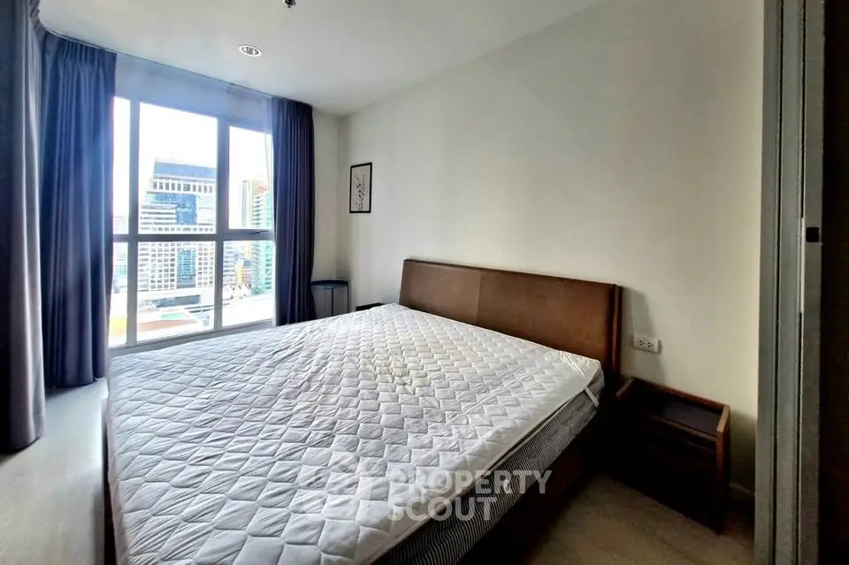 Spacious bedroom with large window and city view in modern apartment