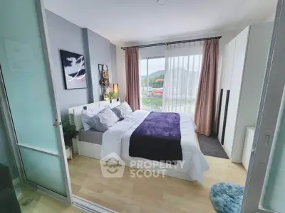 Modern bedroom with large window and scenic view, featuring stylish decor and cozy bedding.
