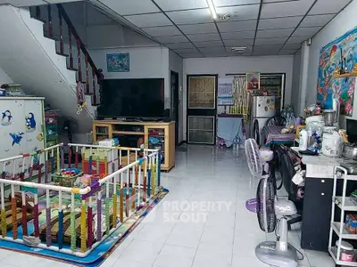 Spacious living room with playpen, TV, and kitchen area in a cozy family home.