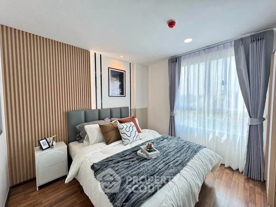 Modern bedroom with stylish decor and large window offering natural light.