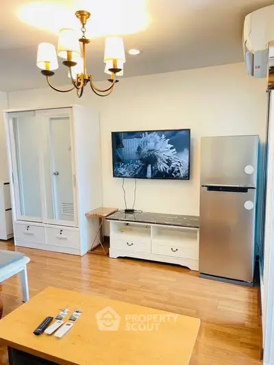Charming living room with modern decor, featuring a sleek fridge and elegant chandelier.