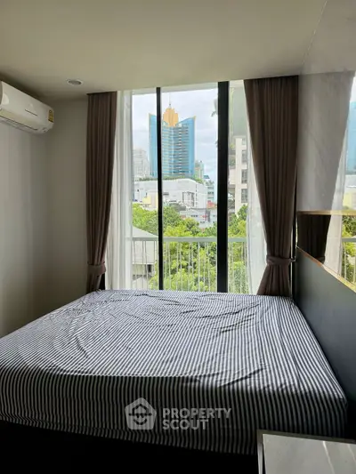 Modern bedroom with large window offering stunning city view and natural light.