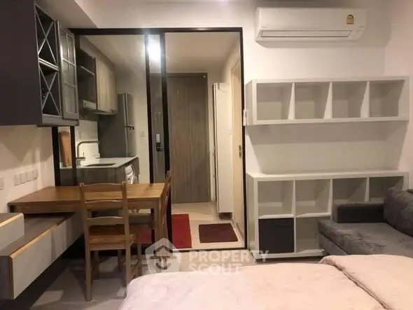 Modern studio apartment with open kitchen and cozy living area, featuring sleek furniture and ample storage.
