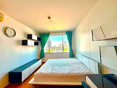 Bright bedroom with large window offering stunning city views, modern furnishings, and ample natural light.