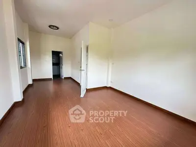 Spacious empty room with wooden flooring and white walls, ideal for customization.