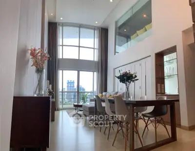 Luxurious high-ceiling living room with modern dining area and large windows offering city views.