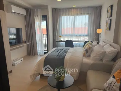 Modern bedroom with stylish decor, large window, and cozy seating area in a contemporary apartment.