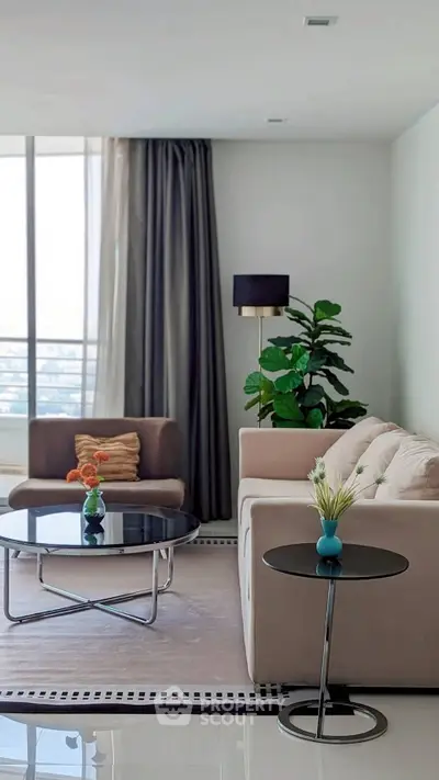Modern living room with elegant furniture and large window offering natural light.