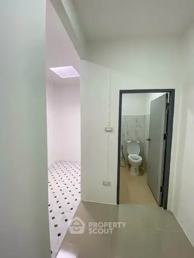 Modern bathroom with sleek design and tiled flooring, featuring a toilet and spacious shower area.