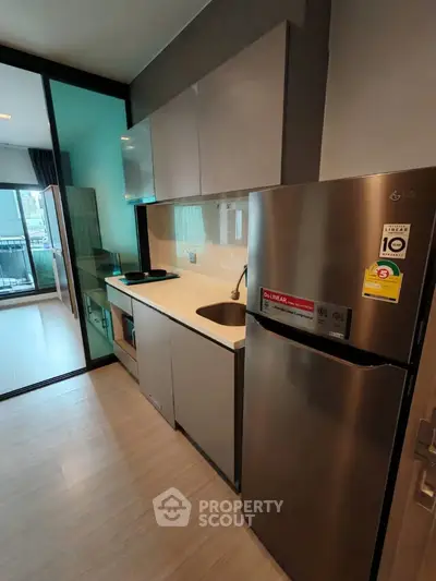 Modern kitchen with sleek cabinets and stainless steel fridge in a stylish apartment.