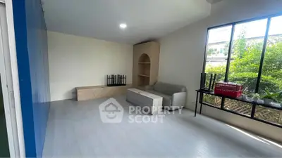 Spacious living room with modern furniture and large windows overlooking a lush garden.