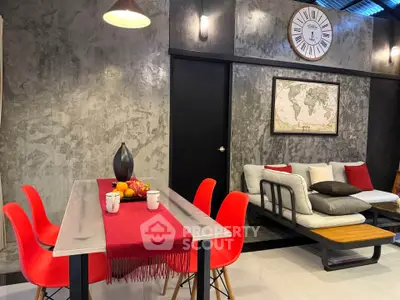 Stylish modern living room with industrial decor, red chairs, and wall clock.