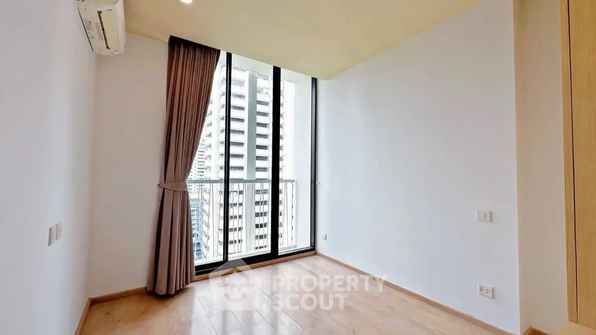 Spacious empty room with floor-to-ceiling windows and city view