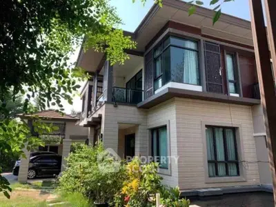 Modern two-story house with large windows and lush garden, perfect for family living.