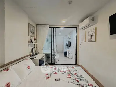 Modern bedroom with floral bedding, sliding glass doors, and a compact study area in a stylish apartment.