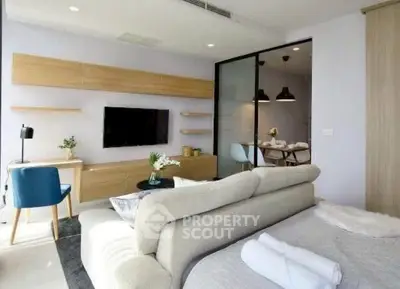 Modern living room with stylish decor and open layout, featuring a cozy sofa and wall-mounted TV.