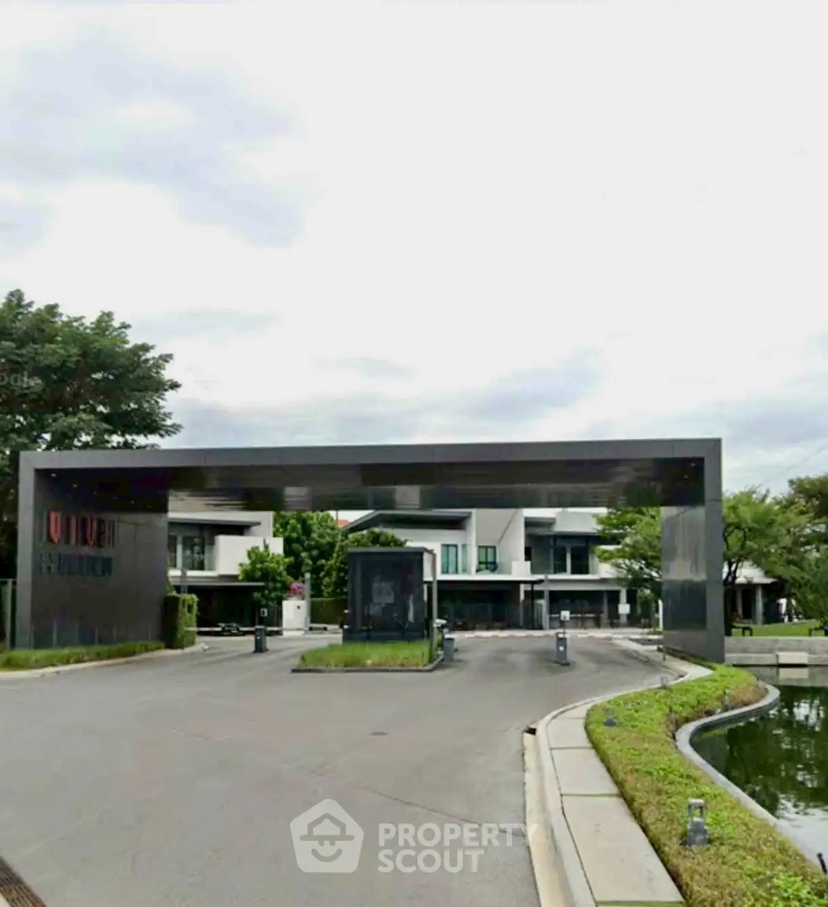 Modern gated community entrance with sleek design and lush greenery