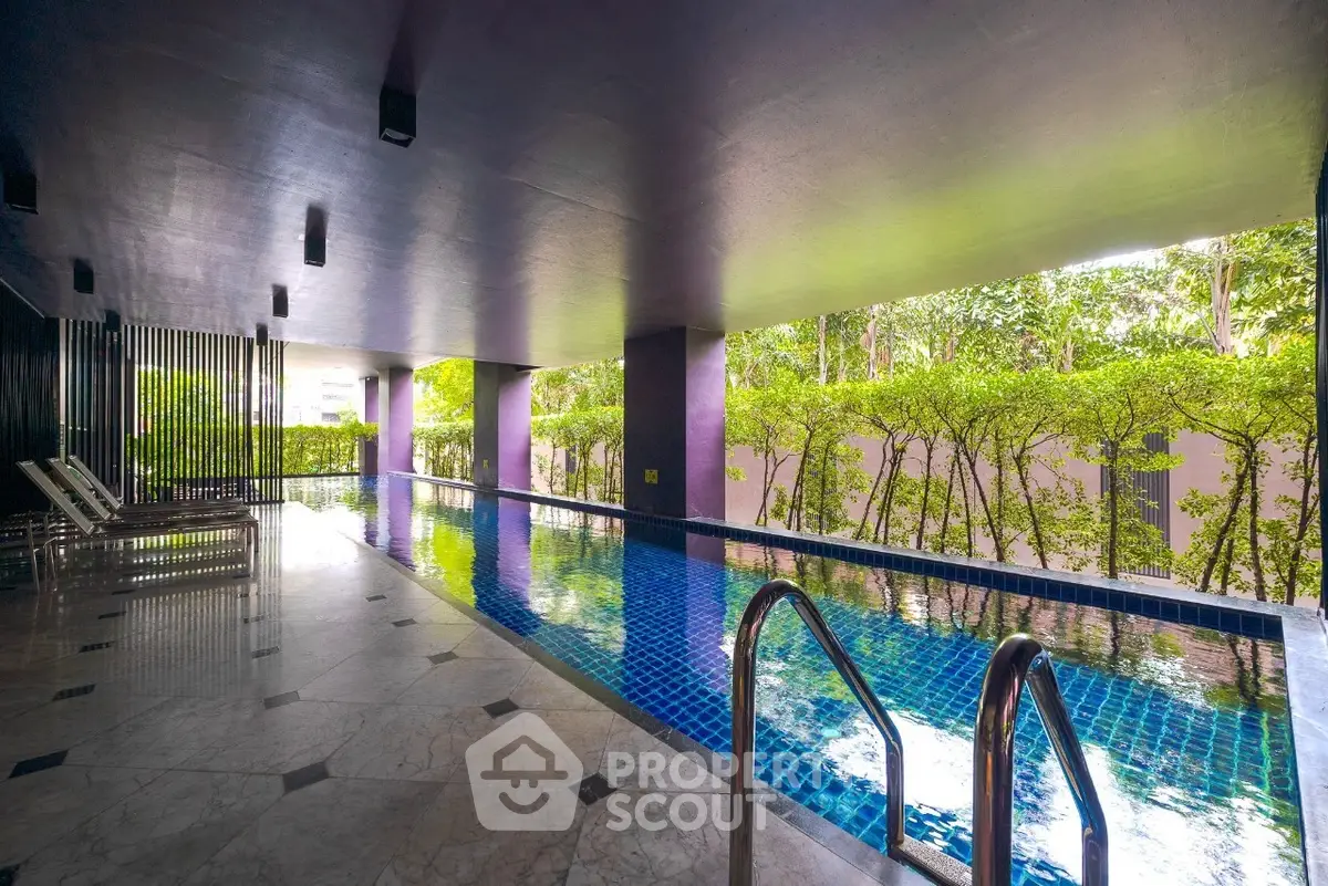 Luxurious indoor pool with lush greenery view in modern real estate property.