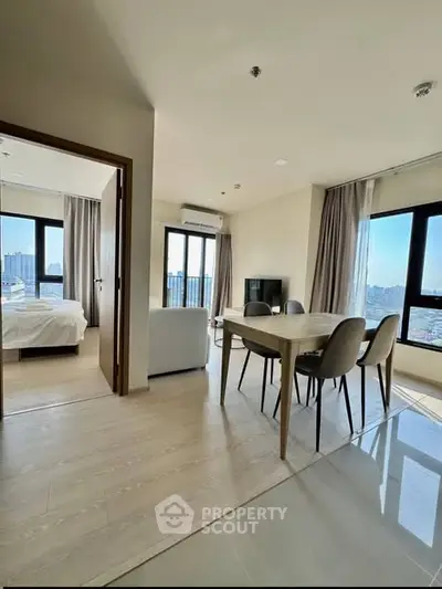 Modern apartment with open living and dining area, large windows, and city view.