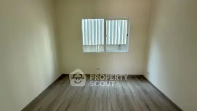 Spacious empty room with wooden flooring and large window, perfect for customization.