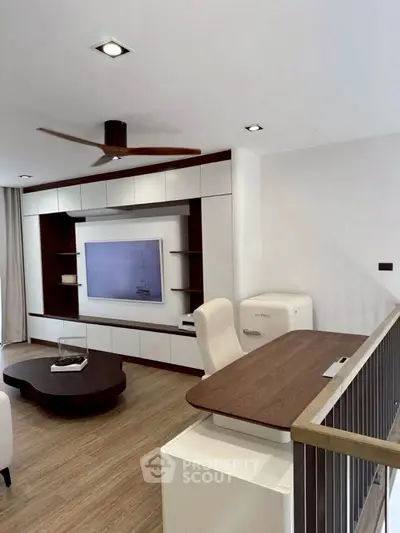 Modern living room with sleek furniture and built-in TV unit, featuring a stylish ceiling fan.