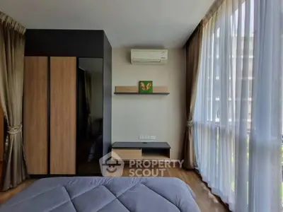 Modern bedroom with large window and air conditioning unit, featuring stylish wooden furniture.