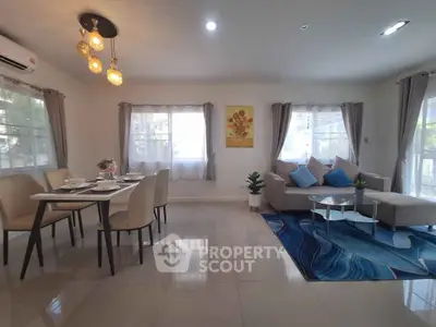 Spacious living room with modern decor and dining area, featuring elegant lighting and large windows.