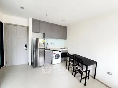 Modern kitchen with stainless steel appliances and dining area in a compact apartment.
