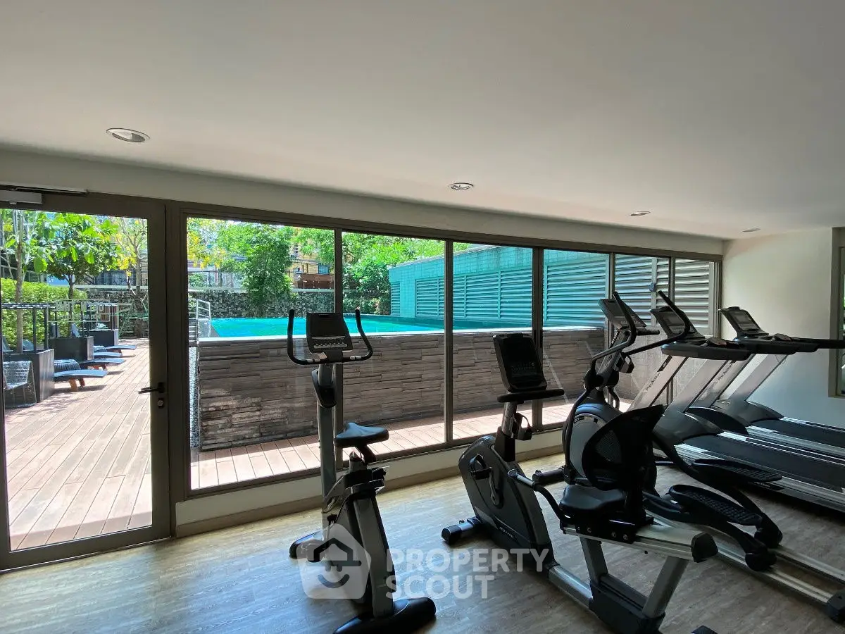 Modern gym with pool view and exercise equipment in luxury property.