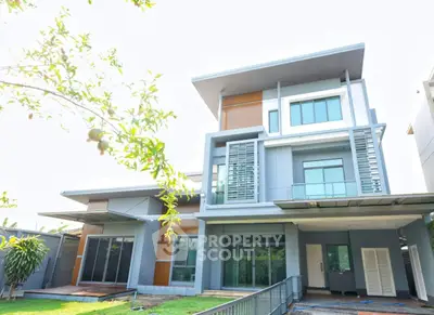 Modern multi-story house with sleek design and large windows in a suburban setting.