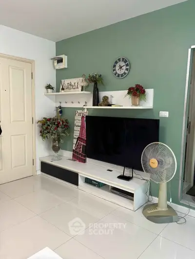 Modern living room with stylish decor and large TV unit, featuring a green accent wall and sleek white flooring.