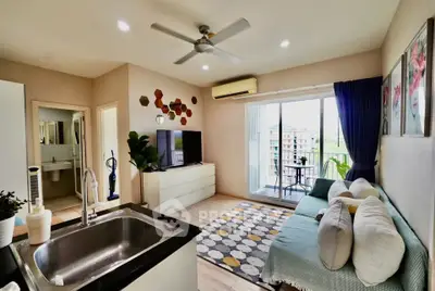 Modern living room with open kitchen, featuring a cozy sofa, TV, and balcony access with a view.