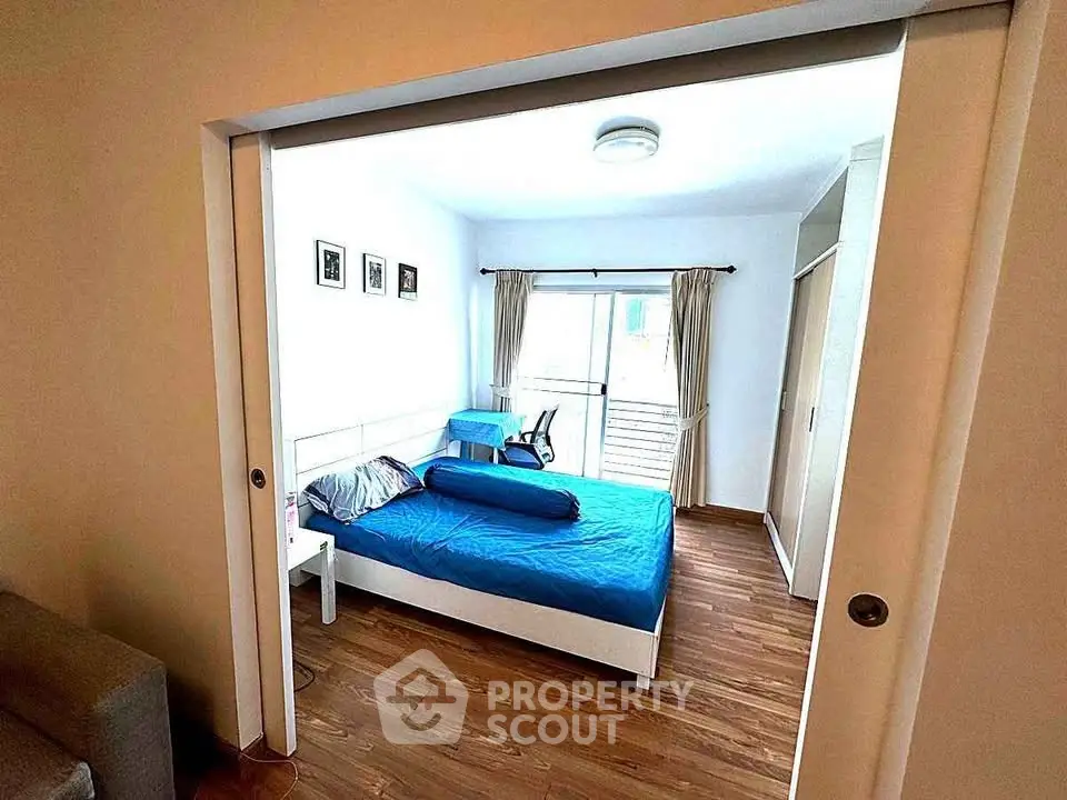 Spacious bedroom with wooden flooring and large window for natural light