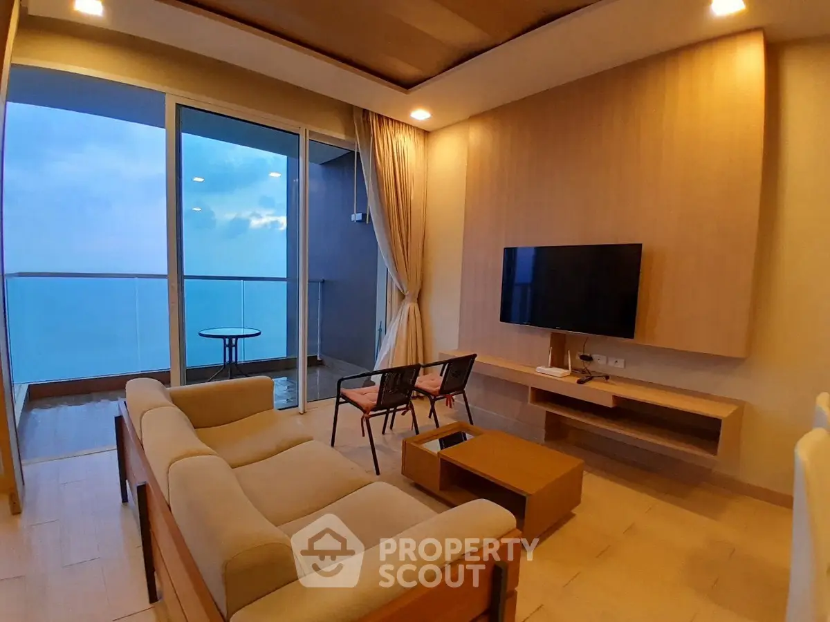 Luxurious living room with ocean view balcony, modern furniture, and ambient lighting.