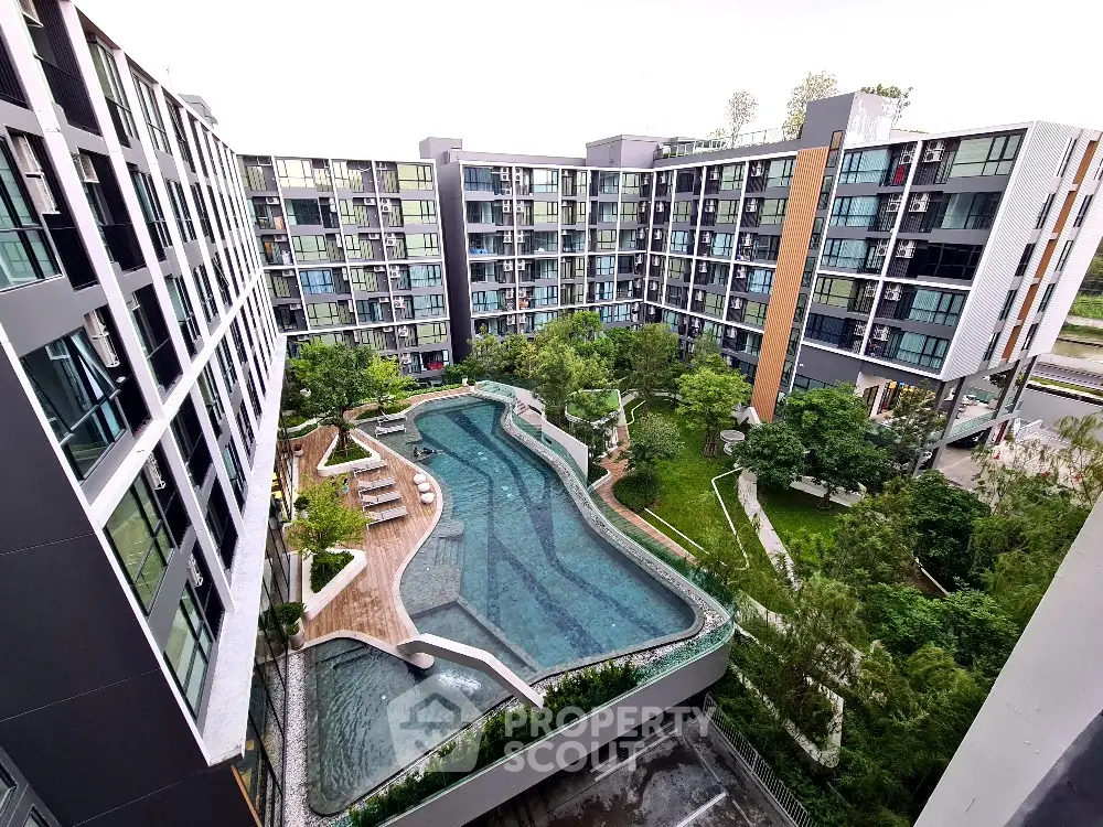 Modern condominium complex with central swimming pool and lush greenery