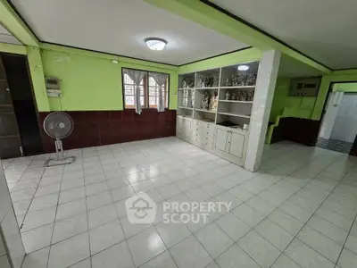 Spacious living room with tiled flooring and built-in shelving, ideal for family gatherings.