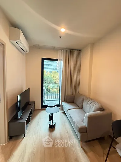 Modern living room with cozy sofa, TV, and balcony view in stylish apartment.