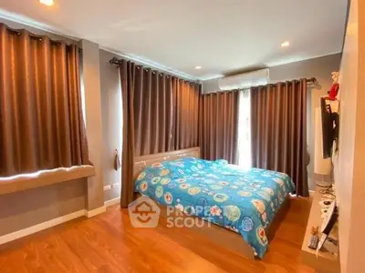 Spacious bedroom with wooden flooring and large windows for natural light.