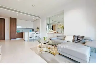 Luxurious modern living room with elegant decor and open kitchen layout, featuring a stylish sectional sofa and glass coffee table.