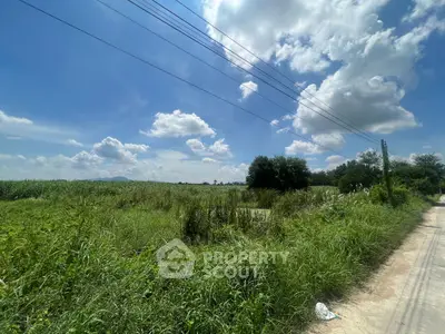 Expansive land plot with lush greenery under a bright blue sky, ideal for development opportunities.